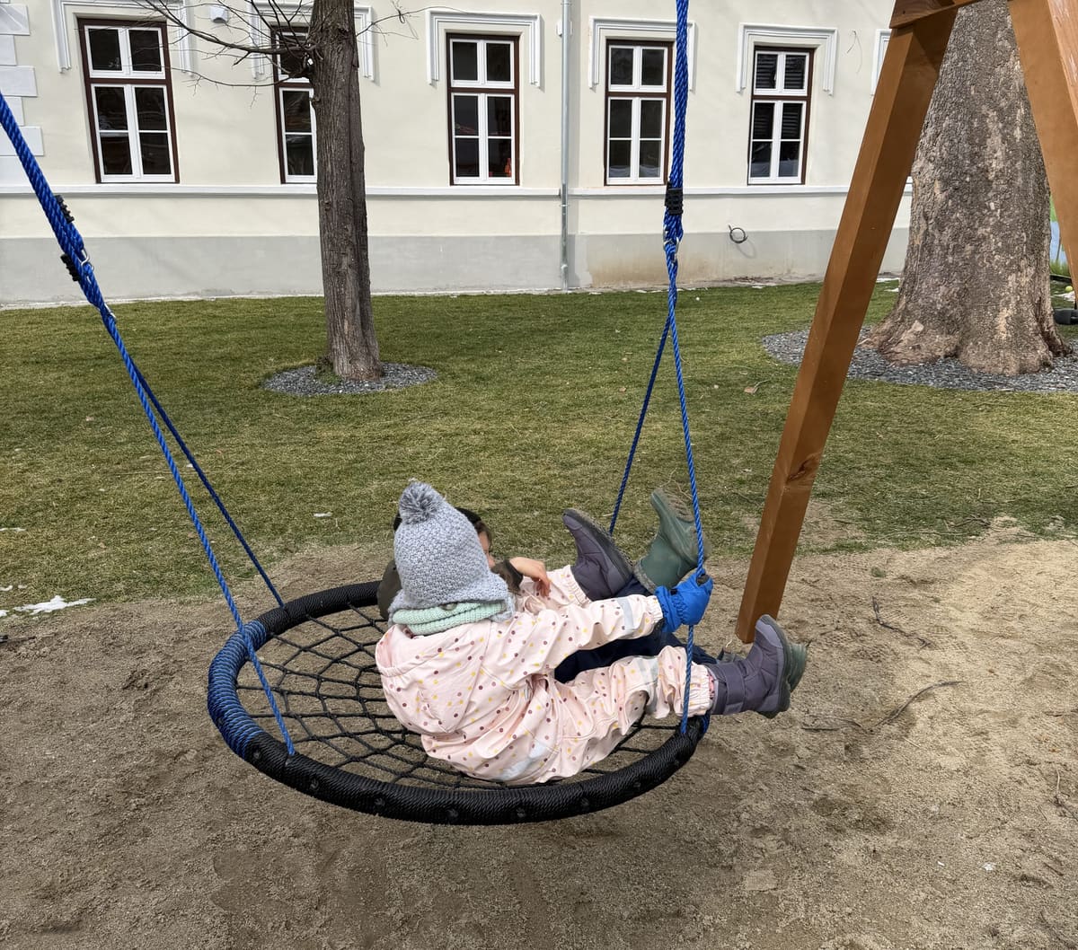 Kind in der Nestschaukel im Hof